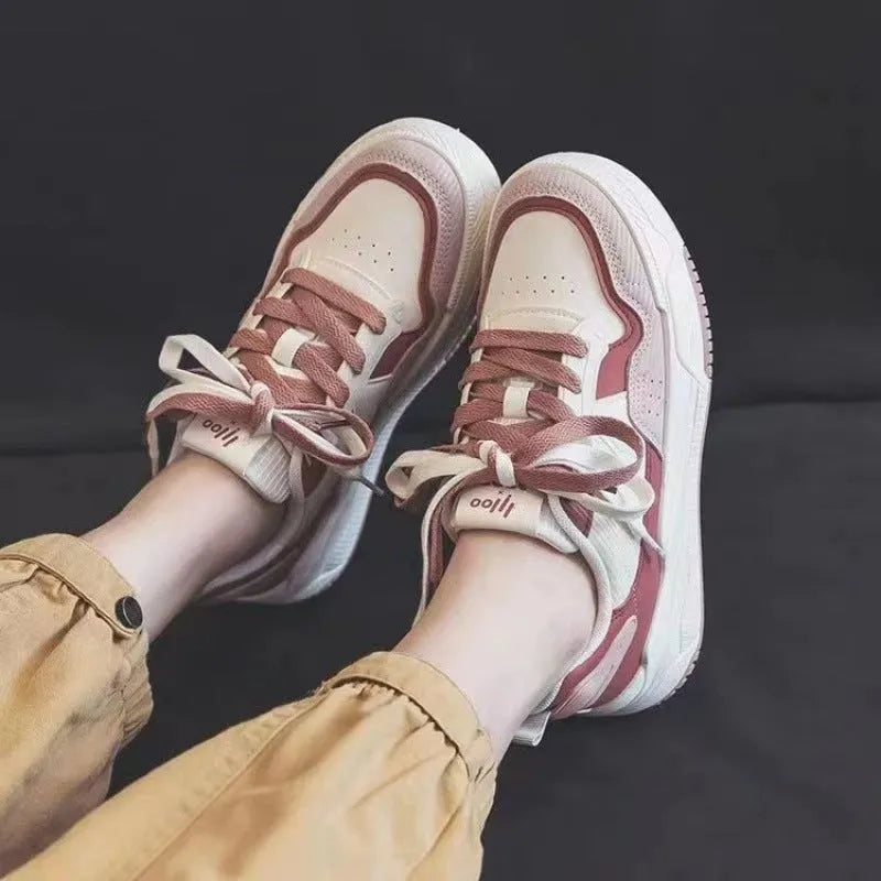 Pink and milky white low-top height-increasing sneakers with a rubber sole.