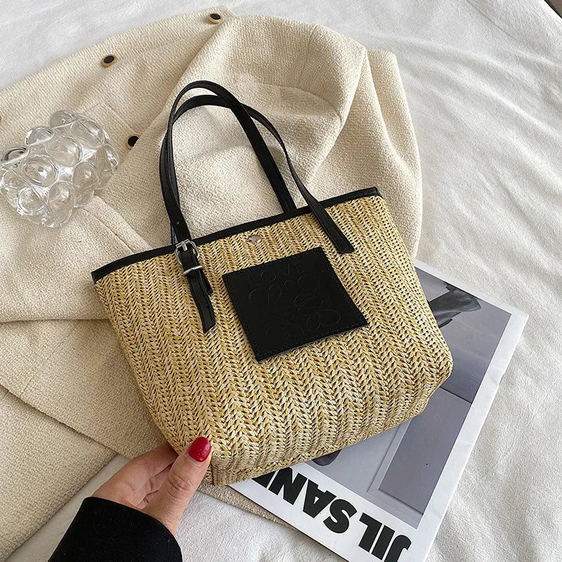 White woven straw women's shoulder bag with a three-dimensional pocket and a black handle.