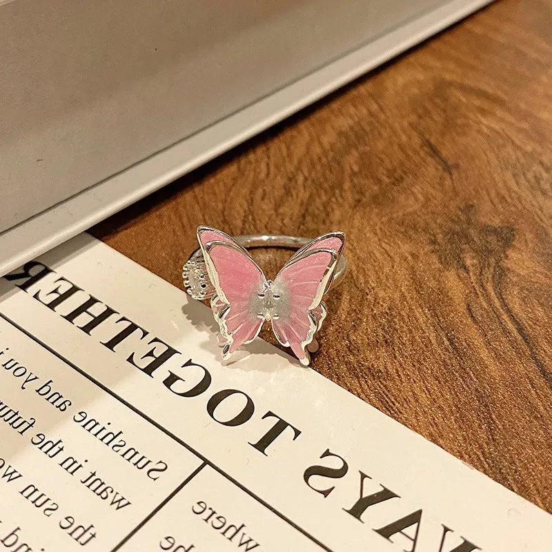 Copper butterfly women's ring with an open loop design on a plain background.
