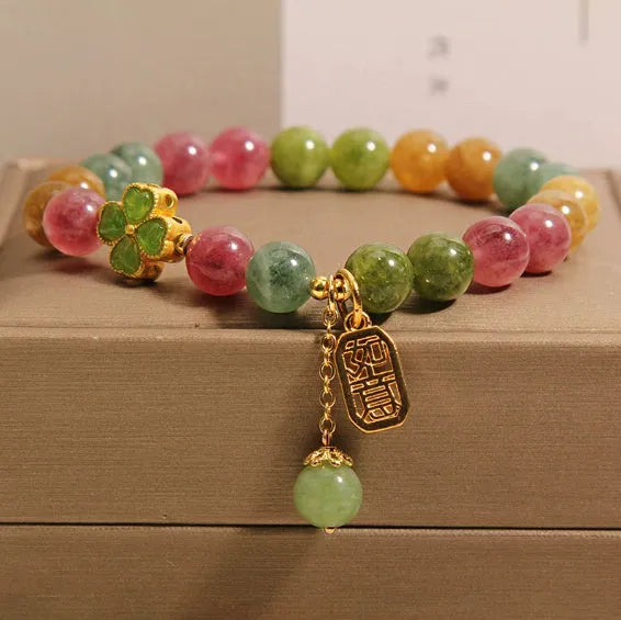Colourful mixed-material women's bracelet with a four-leaf clover charm and a pearl pendant on a geometric chain.