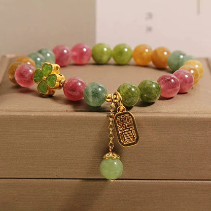 Colourful mixed-material women's bracelet with a four-leaf clover charm and a pearl pendant on a geometric chain.