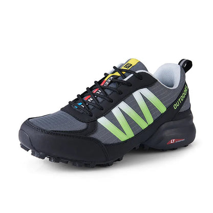 Men's black mountaineering sneakers with a rubber sole and lace-up front on a rocky surface.