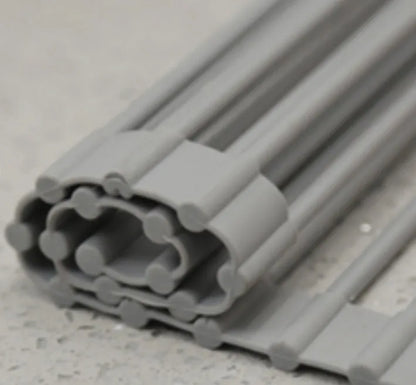 Folding stainless steel kitchen drain rack with coloured plastic tubes, shown open for use.