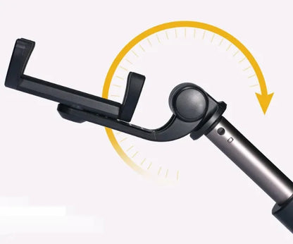 Aluminium tripod selfie stick with extended phone clip and Bluetooth remote on a table