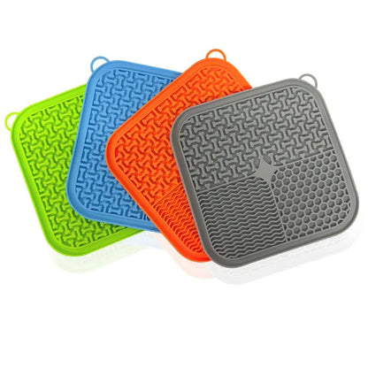 Square orange, grey, blue, and green silicone dog licking mat with suction cups on the base.