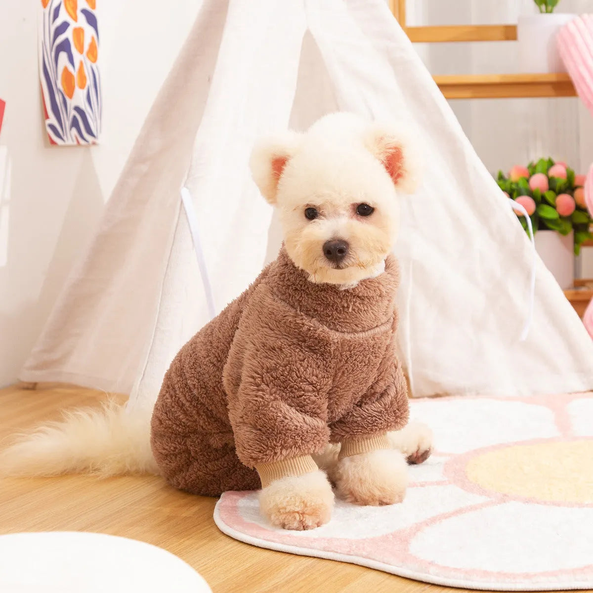 A dog wearing a blue, double-sided plush, four-legged coat with a high collar and a small towing ring visible.