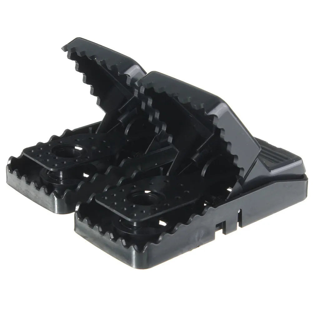Six black plastic snapping mousetraps laid out on a surface, showing their size and smooth construction.
