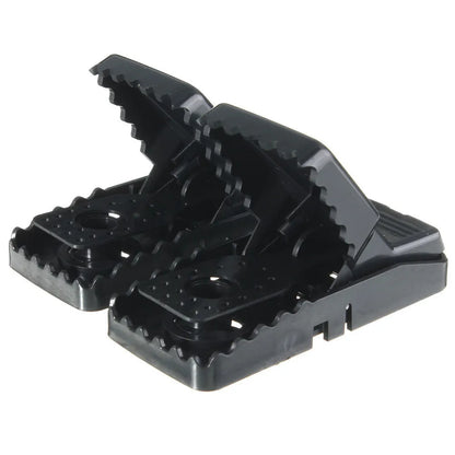 Six black plastic snapping mousetraps laid out on a surface, showing their size and smooth construction.