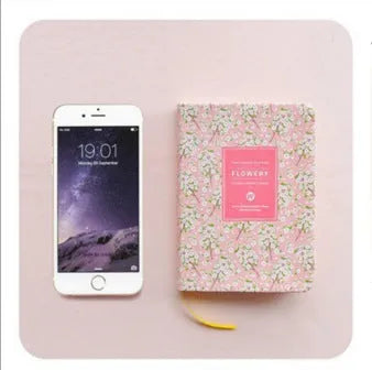 Green floral notepad with fabric imitation leather cover lying open on a table.