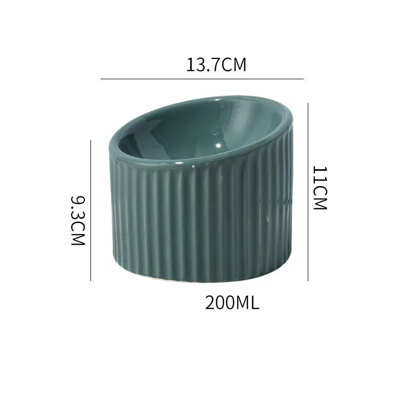 Ceramic elevated cat bowl in green colour showing tilted, round whisker-friendly design.