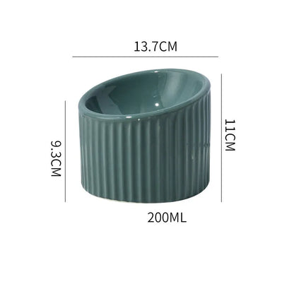 Ceramic elevated cat bowl in green colour showing tilted, round whisker-friendly design.