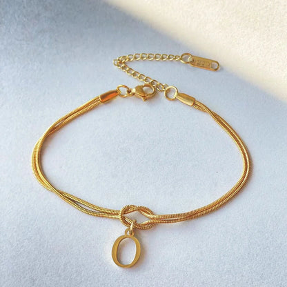 Elegant letter charm bracelets for women in gold and silver tones, featuring a delicate snake chain design and personalised letter charms.