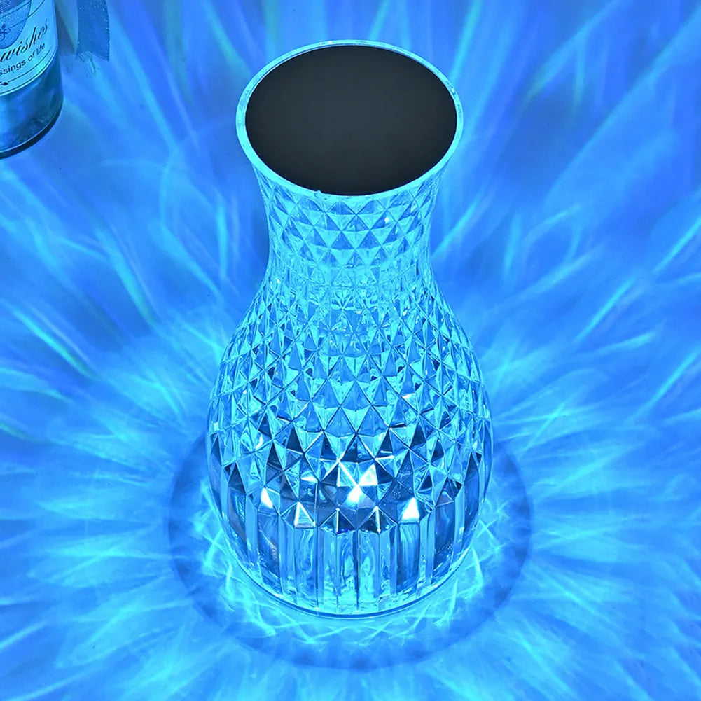 Vase-shaped crystal table lamp with remote control on a bedside table, showing diamond-like glow and USB charging port.