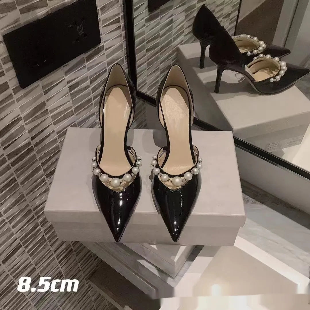 Women's black pointed toe patent leather stiletto high heels with pearl decoration on the upper.
