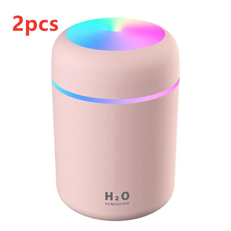 Pink USB desktop humidifier with LED lights and water tank on wooden desk