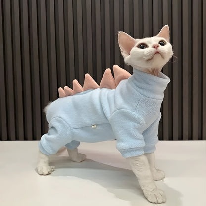 Sphynx cat wearing green dinosaur costume with tail and spikes
