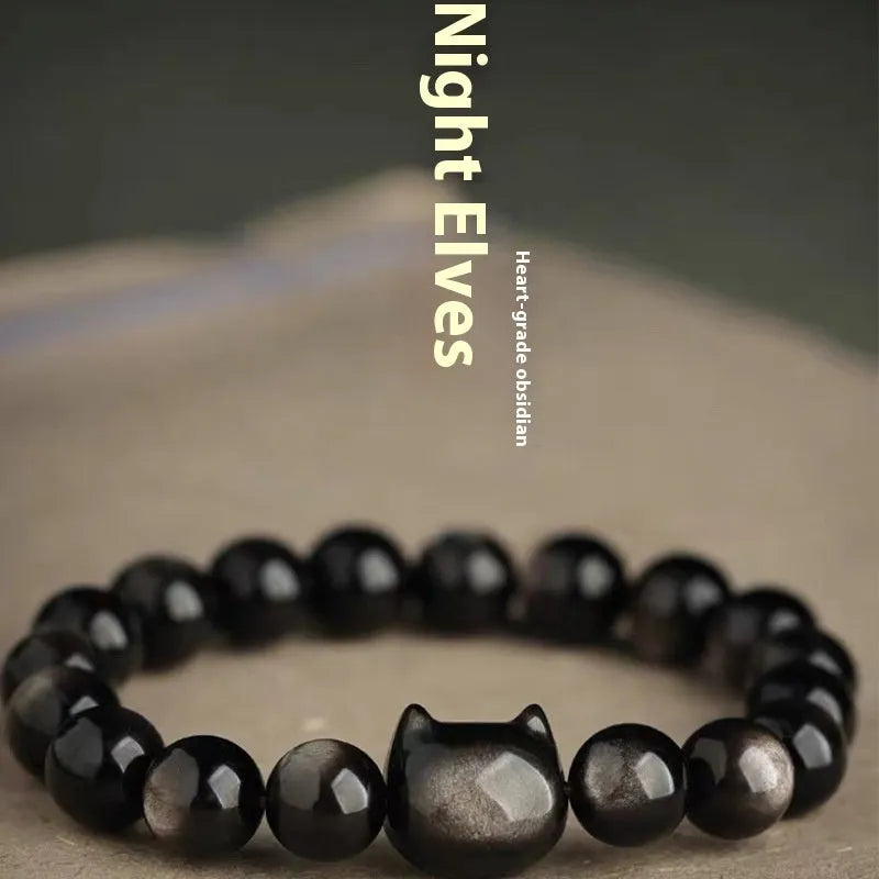 Obsidian cat head bracelet with round stone beads and a gold-toned cat charm on a wrist.
