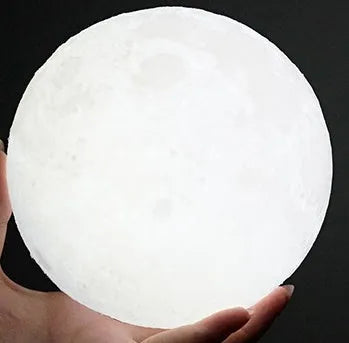 3D printed white moon lamp on a wooden holder, showing detailed crater texture and soft LED glow.