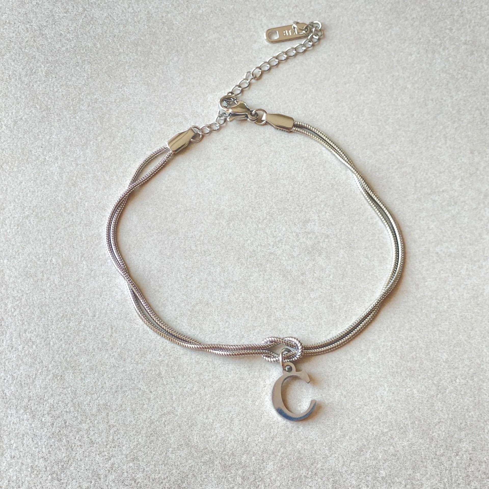 Elegant letter charm bracelets for women in gold and silver tones, featuring a delicate snake chain design and personalised letter charms.
