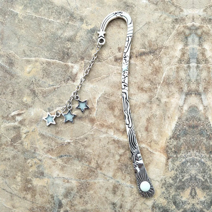 Retro five-pointed star glowing metal bookmark in ancient silver and bronze finishes on an open book.