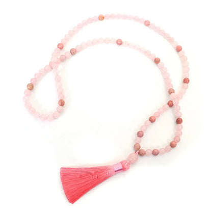 Natural stone bead necklace and bracelet set with a long fringe tassel pendant on a table.