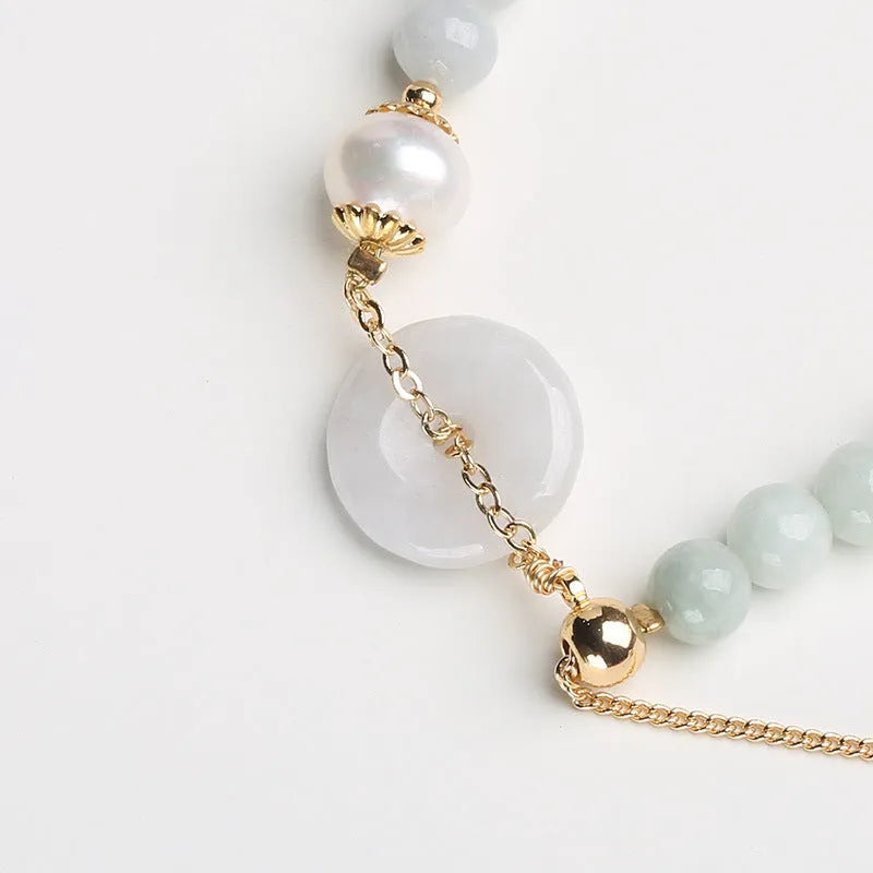 Natural jade bracelet with a geometric peace buckle clasp and round pendant.