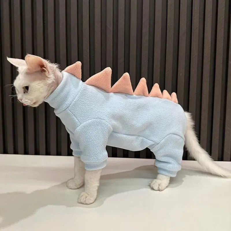 Sphynx cat wearing green dinosaur costume with tail and spikes