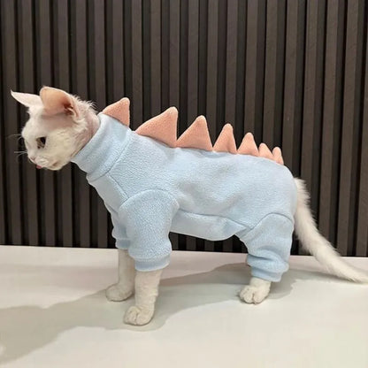 Sphynx cat wearing green dinosaur costume with tail and spikes