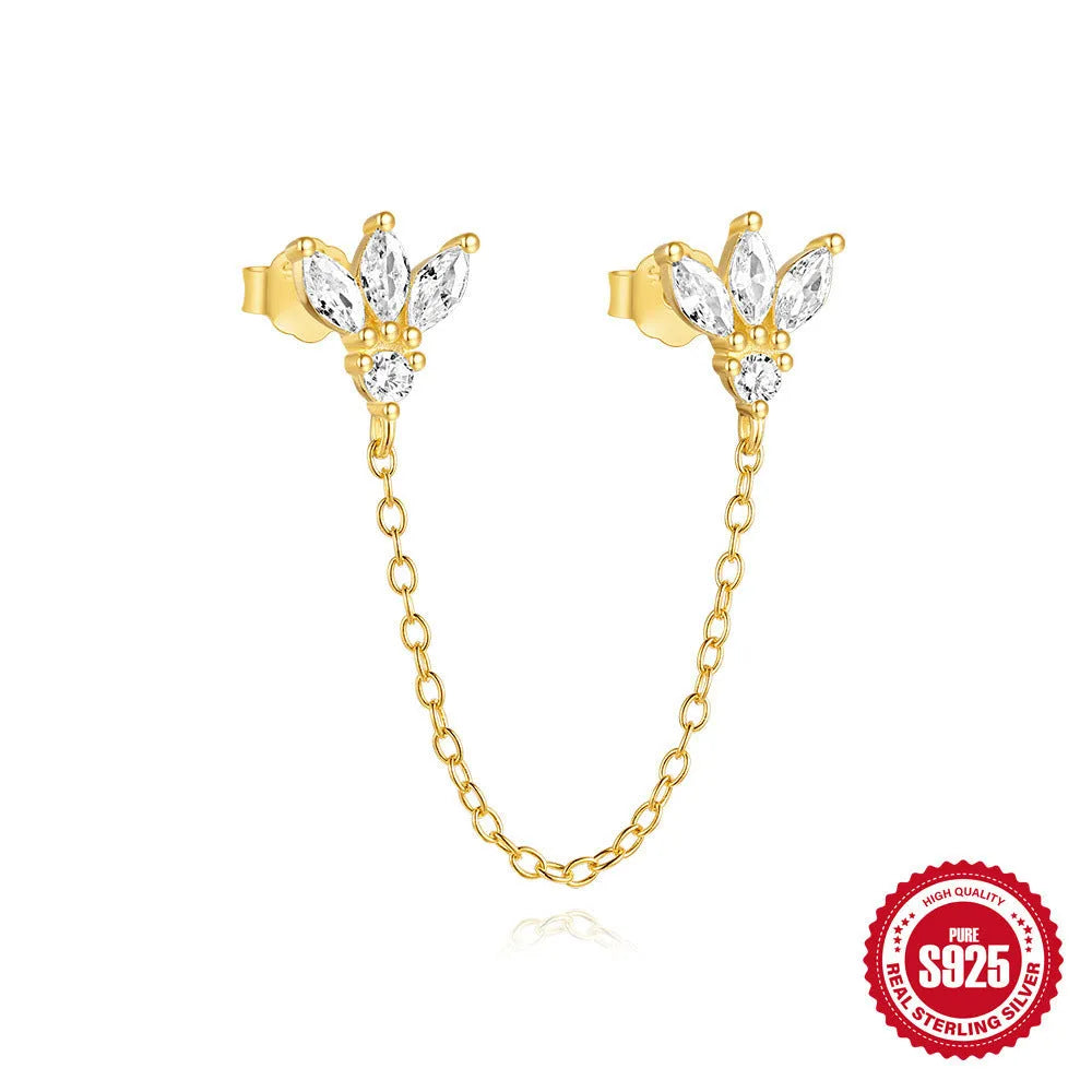 Close-up of a sterling silver double piercing chain stud earring with inlaid zircon stone in a golden colour.