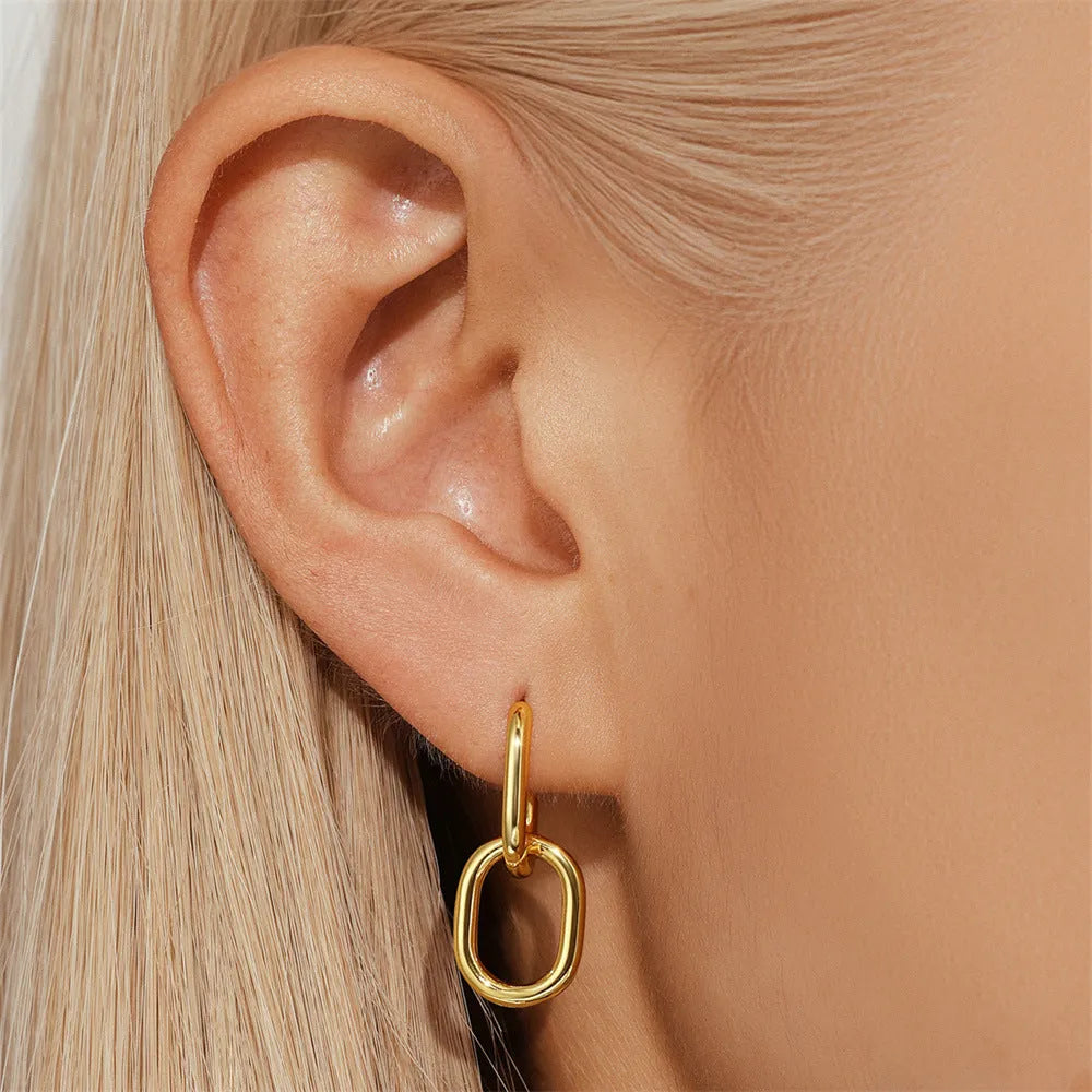 Geometric gold-tone stud earrings with a round centre on an earclip back, shown from the front.