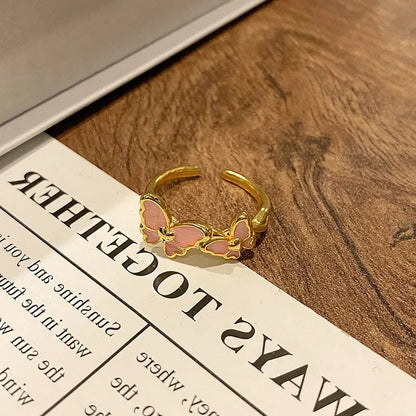 Copper butterfly women's ring with an open loop design on a plain background.