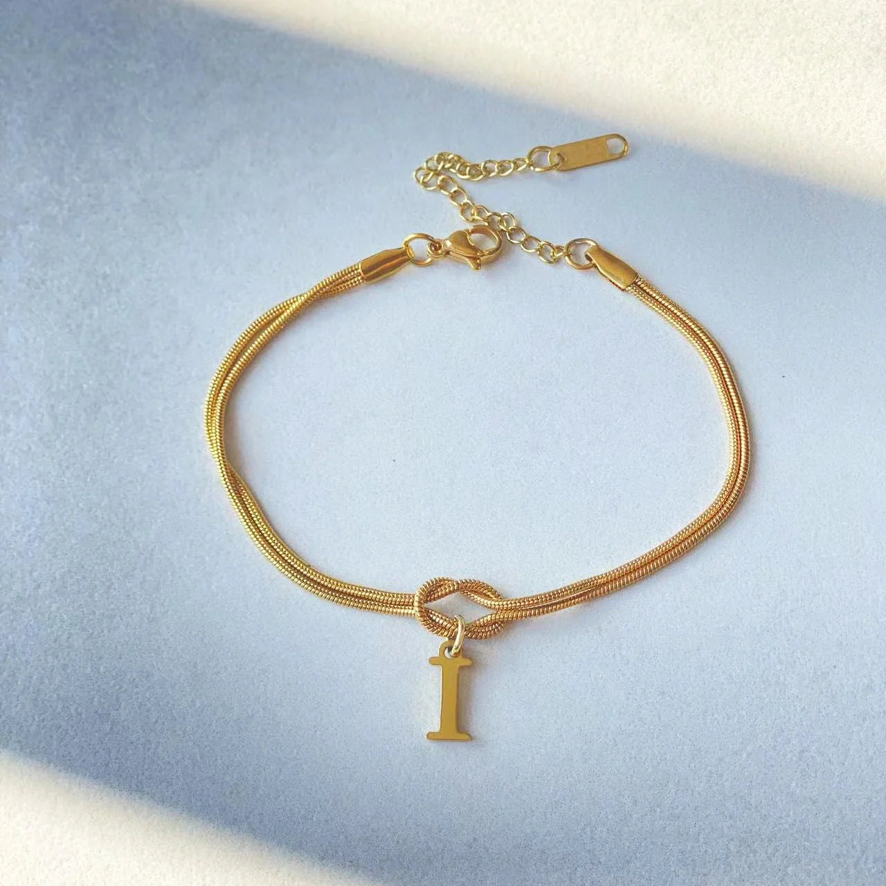 Elegant letter charm bracelets for women in gold and silver tones, featuring a delicate snake chain design and personalised letter charms.