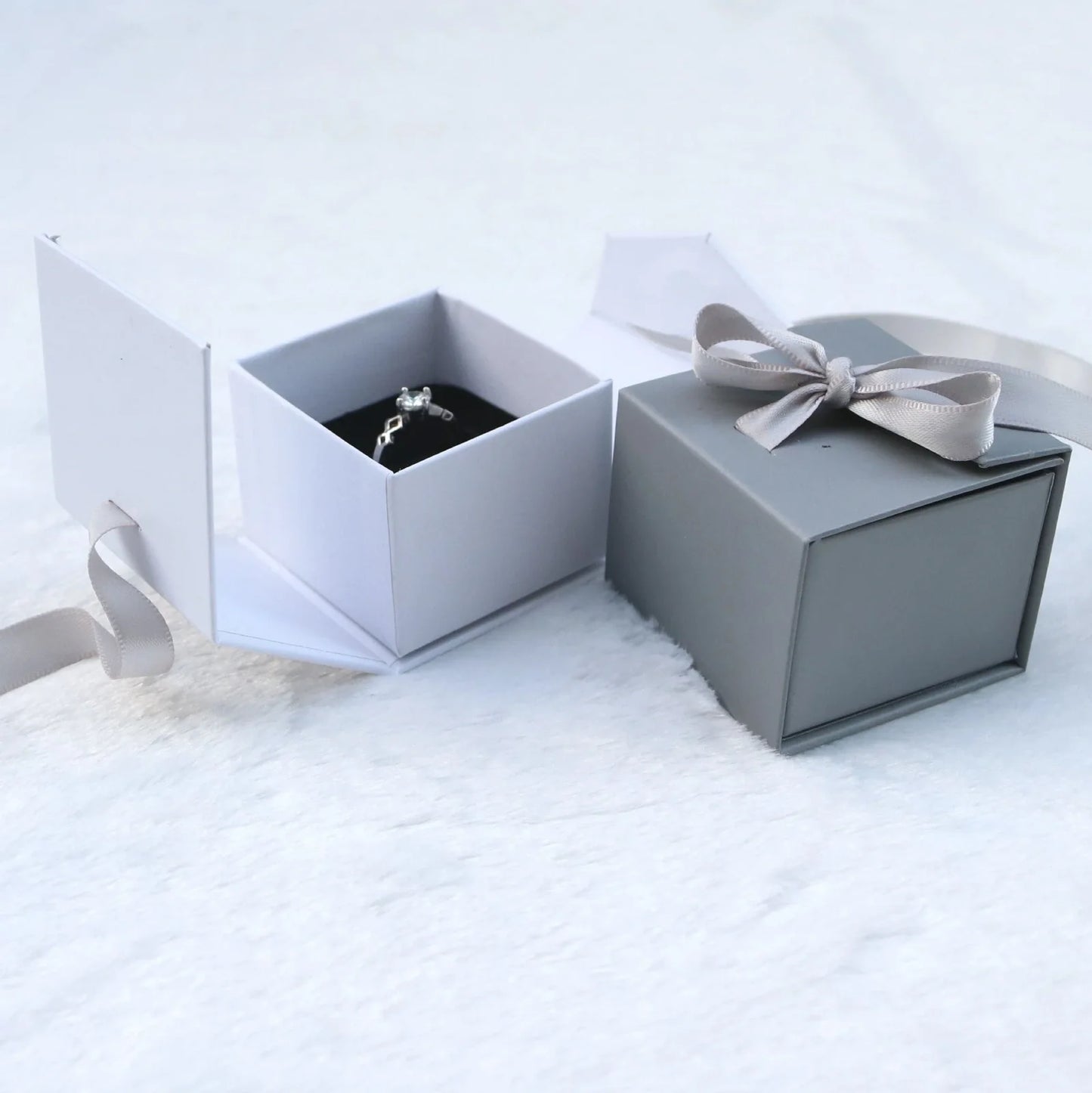 Grey square jewellery box with white ribbon bow measuring 5x5x4cm with sponge-lined interior