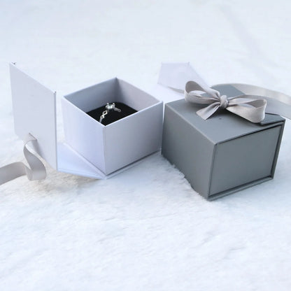 Grey square jewellery box with white ribbon bow measuring 5x5x4cm with sponge-lined interior