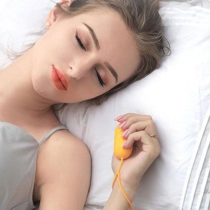 Hand-held micro-current sleep aid device in grey, green, or orange with round button and USB charging port