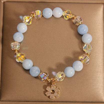 Women's aquamarine crystal bracelet with four-leaf clover charm and pearl details on wrist