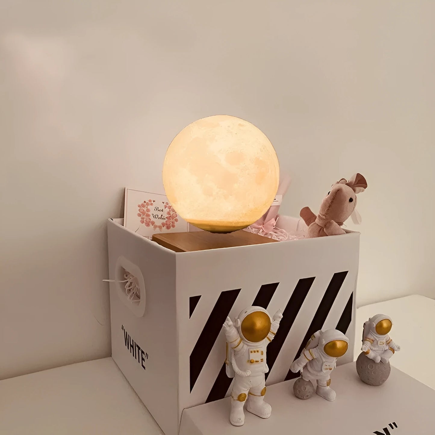 Maglev floating moon planet atmosphere night light with three astronaut figurines on a desk.