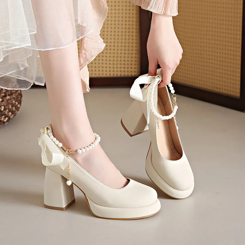 Women's beige preppy style Mary Jane shoes with chunky heel, ankle strap buckle, and pearl detail.