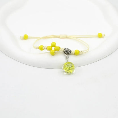 Close-up of a hand-woven bracelet with a large 1.4cm glass bead containing colourful dried flowers.