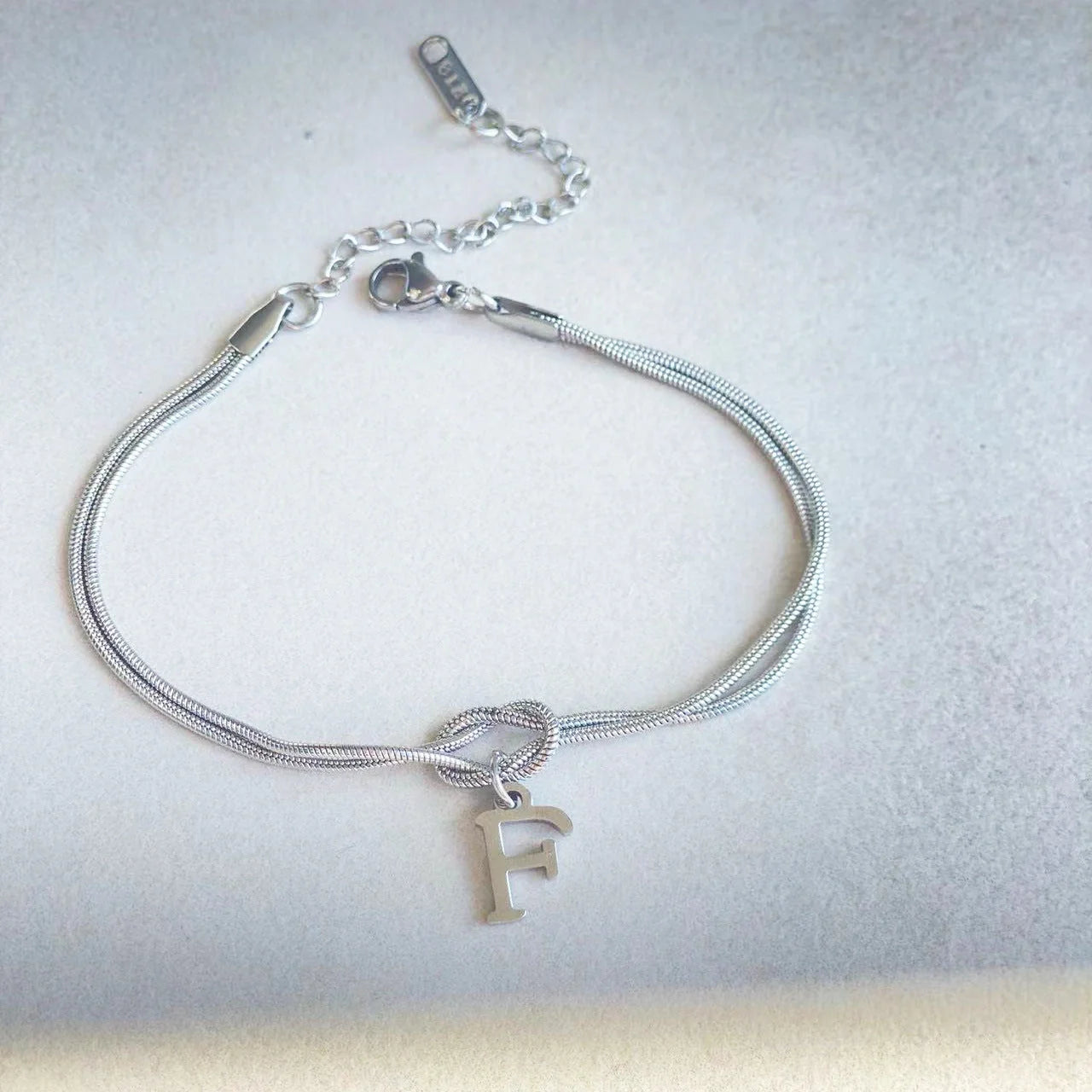 Elegant letter charm bracelets for women in gold and silver tones, featuring a delicate snake chain design and personalised letter charms.