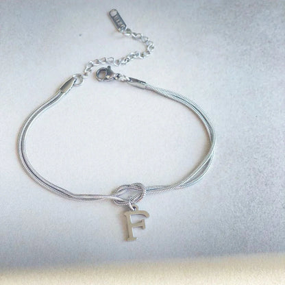 Elegant letter charm bracelets for women in gold and silver tones, featuring a delicate snake chain design and personalised letter charms.