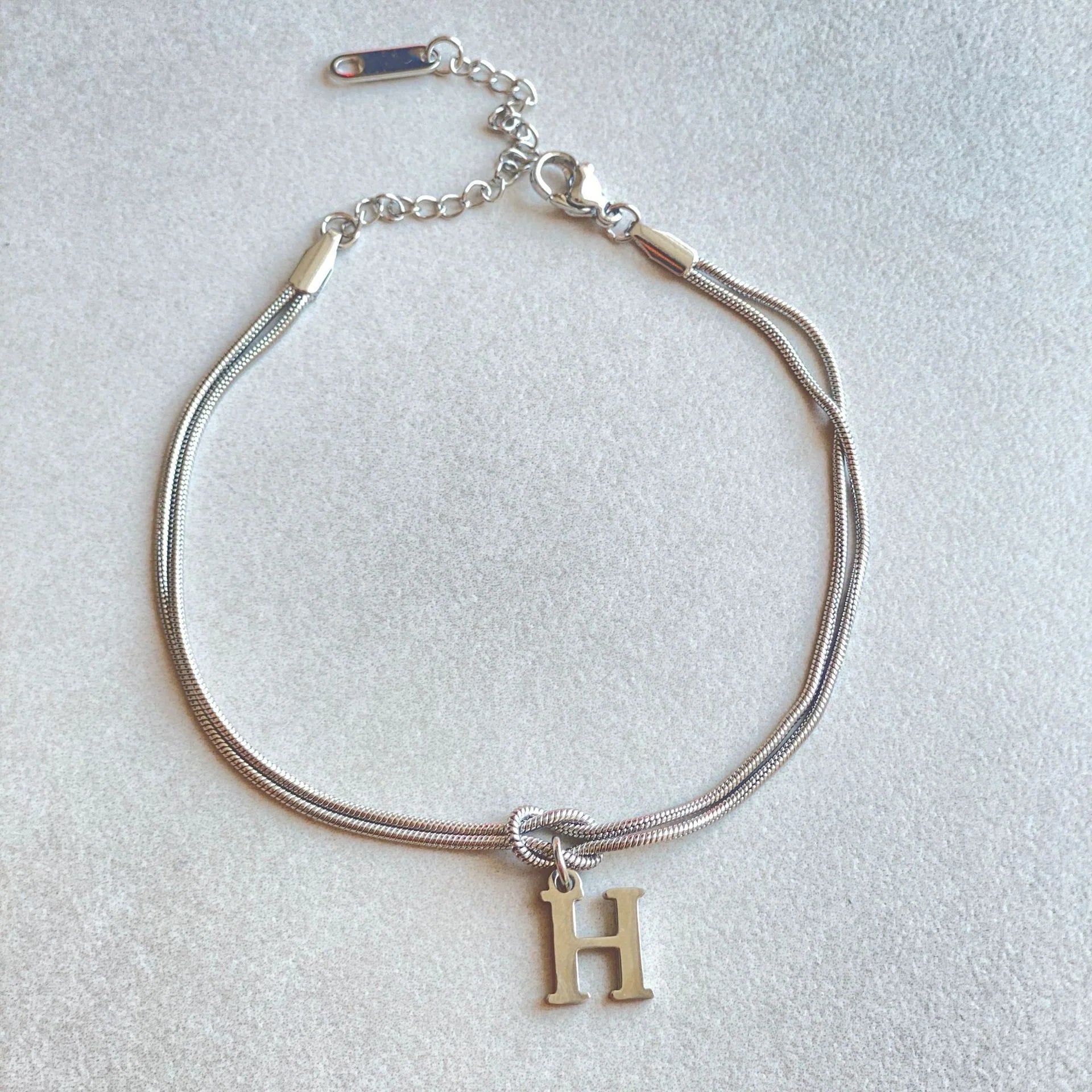 Elegant letter charm bracelets for women in gold and silver tones, featuring a delicate snake chain design and personalised letter charms.