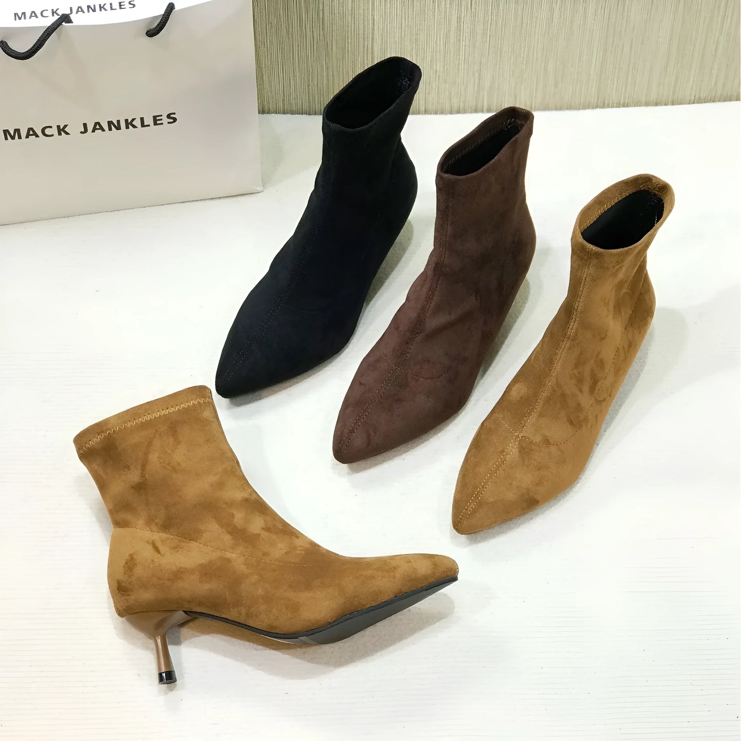 Women's black pointed toe ankle boots with a stiletto heel on a neutral background