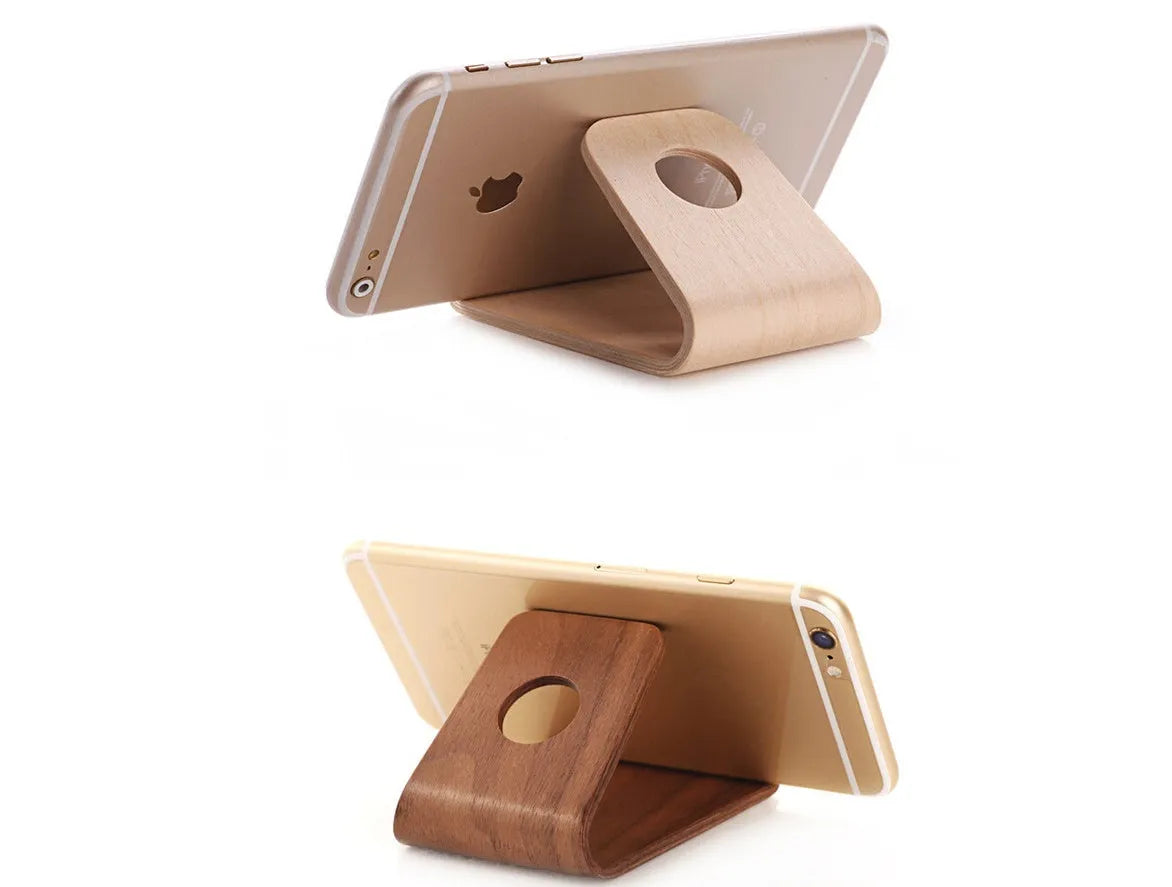 Solid wooden iPhone stand in Walnut finish on a desk, holding a mobile phone.