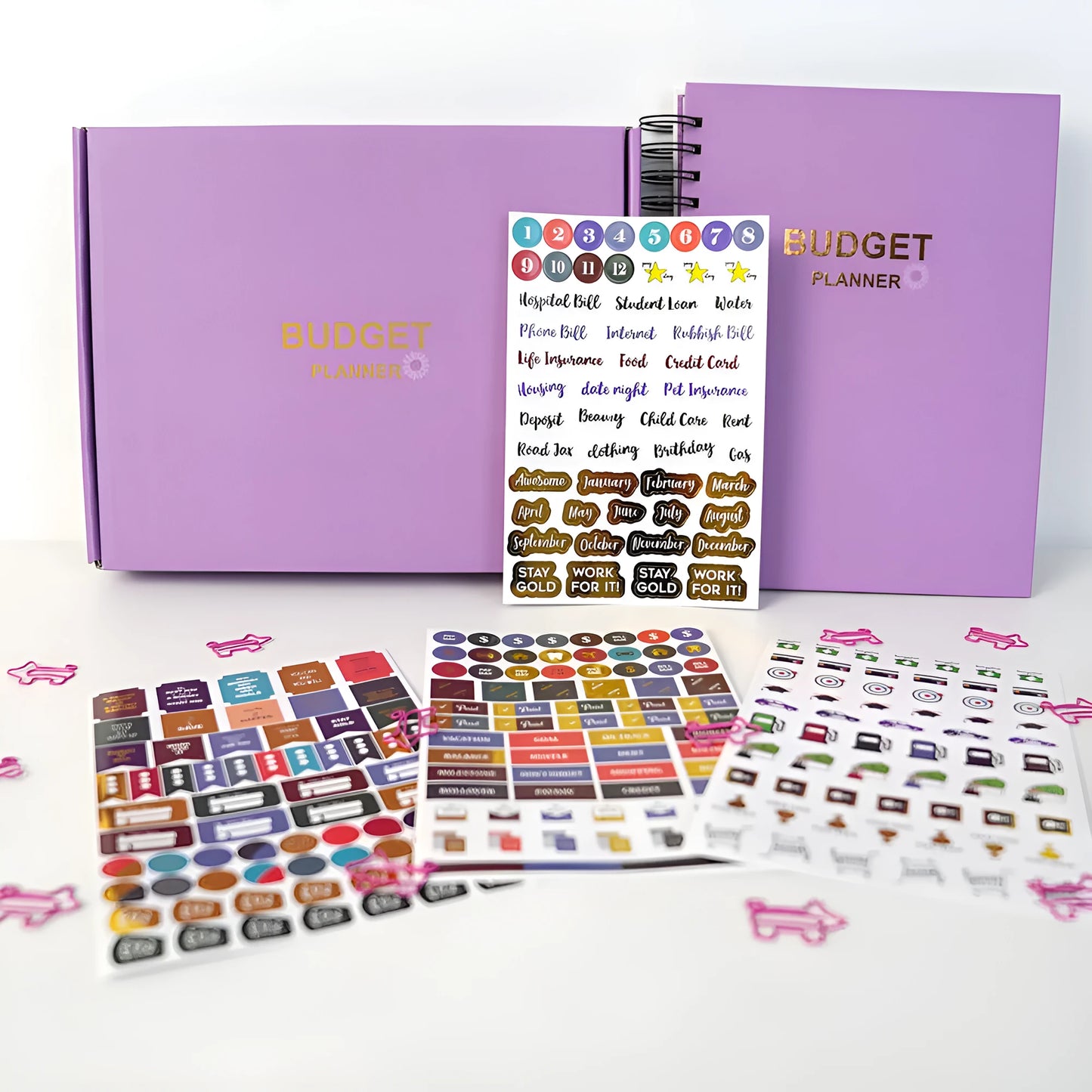 Purple coil-bound A5 budget notebook with pen, stickers and paper clips for financial planning