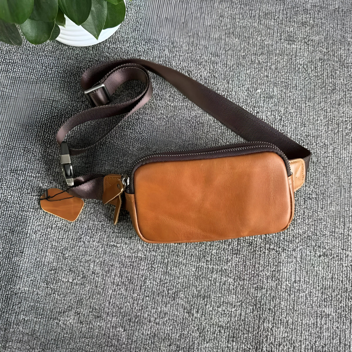 Men's small leather crossbody bag in black showing compact dimensions and crossbody strap