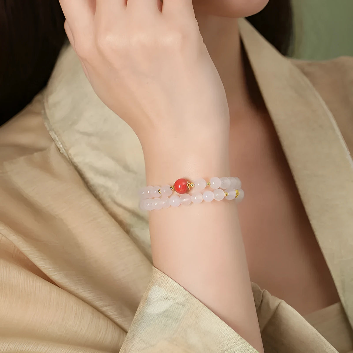 Close-up of a women's double layer bracelet with polished white agate and jequirity bean beads.