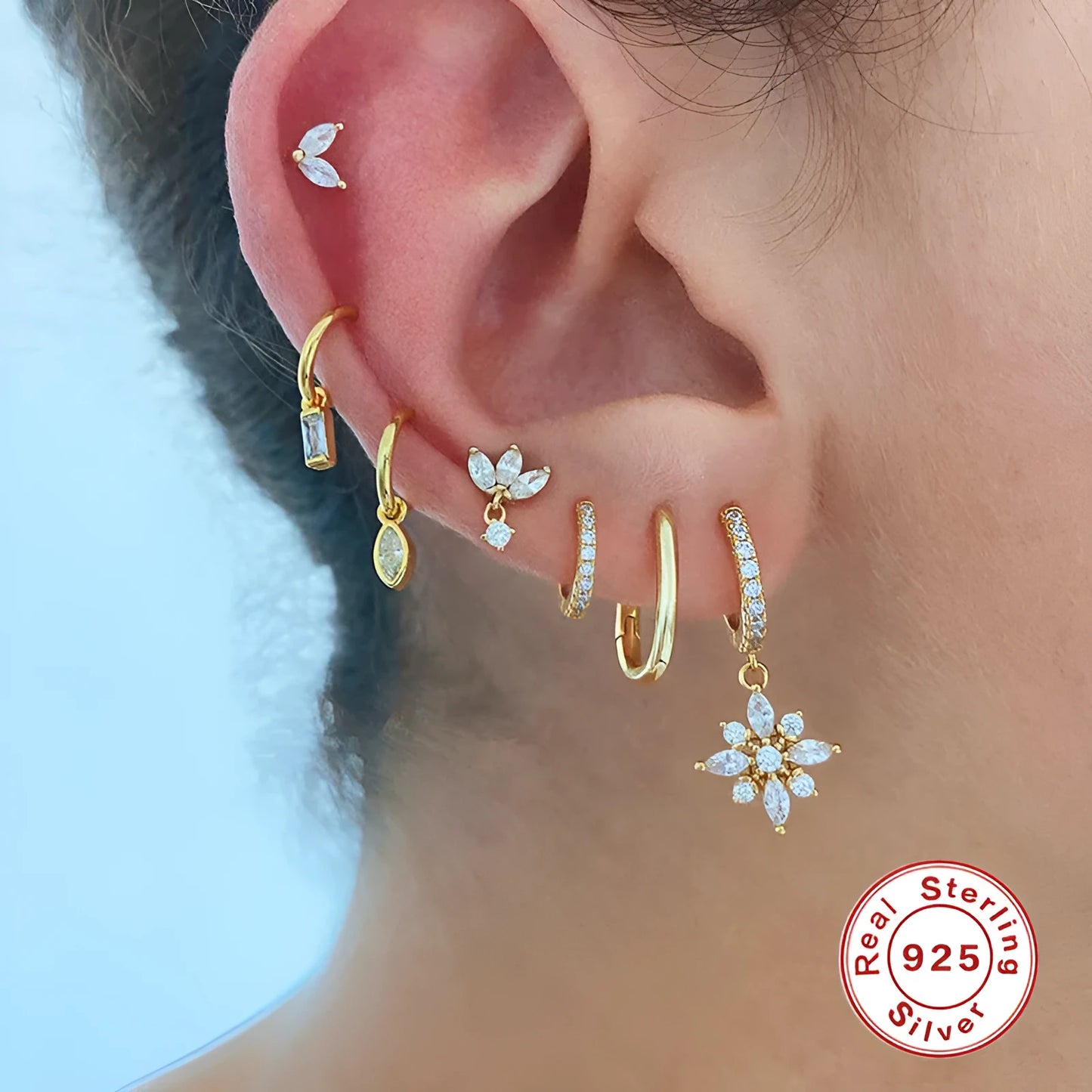 A pair of geometric snowflake pendant earrings in sterling silver with cubic zirconia stones, on a white background.