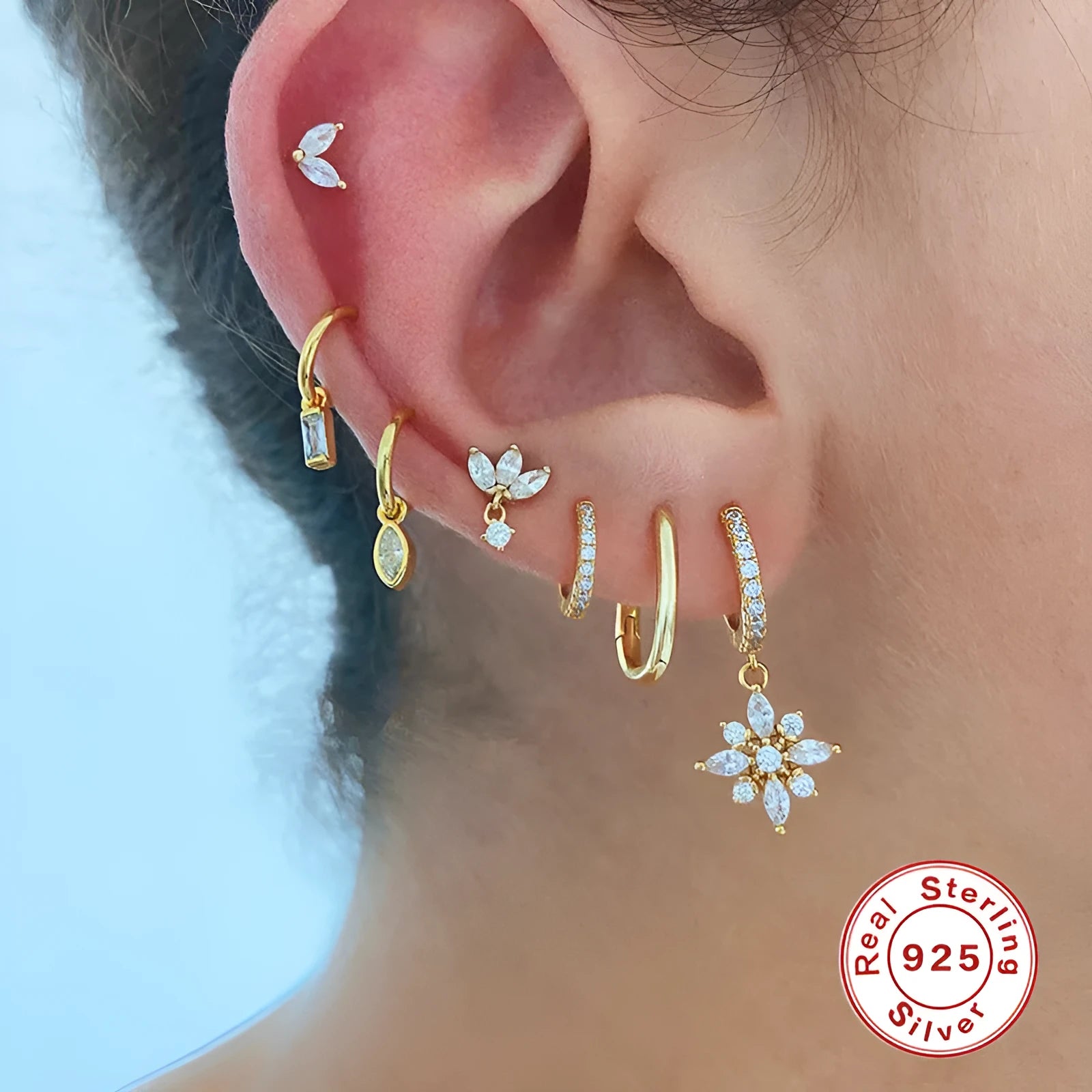 A pair of geometric snowflake pendant earrings in sterling silver with cubic zirconia stones, on a white background.