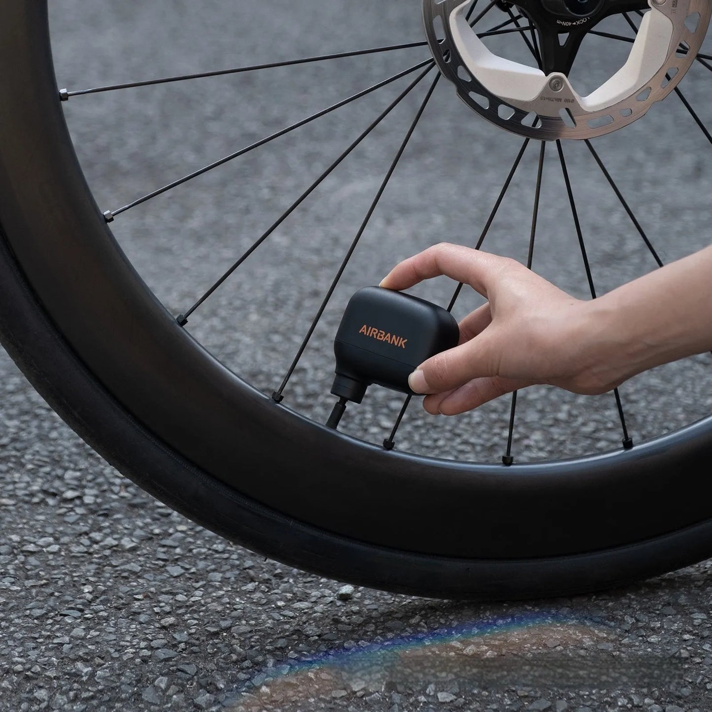 Black AS100 electric bicycle pump with digital display, USB charging port, and included waterproof bag